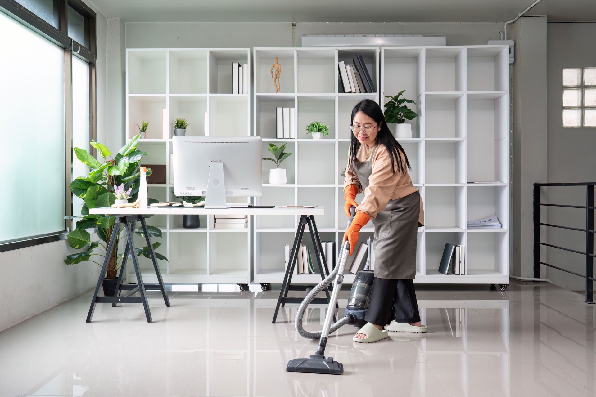 Professional Maid Cleaning Modern Office Space with Vacuum Cleaner in Bright, Organized Environment